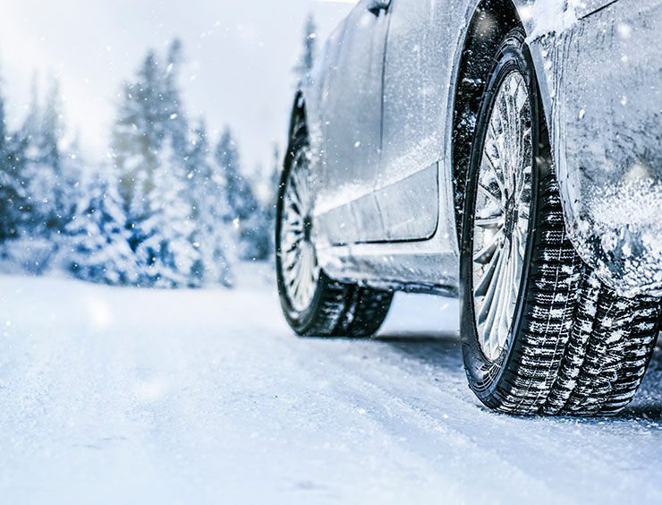 a white car driving down a snow covered road