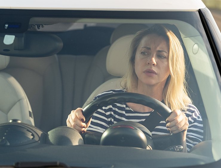 La mujer al volante escucha el ruido del coche